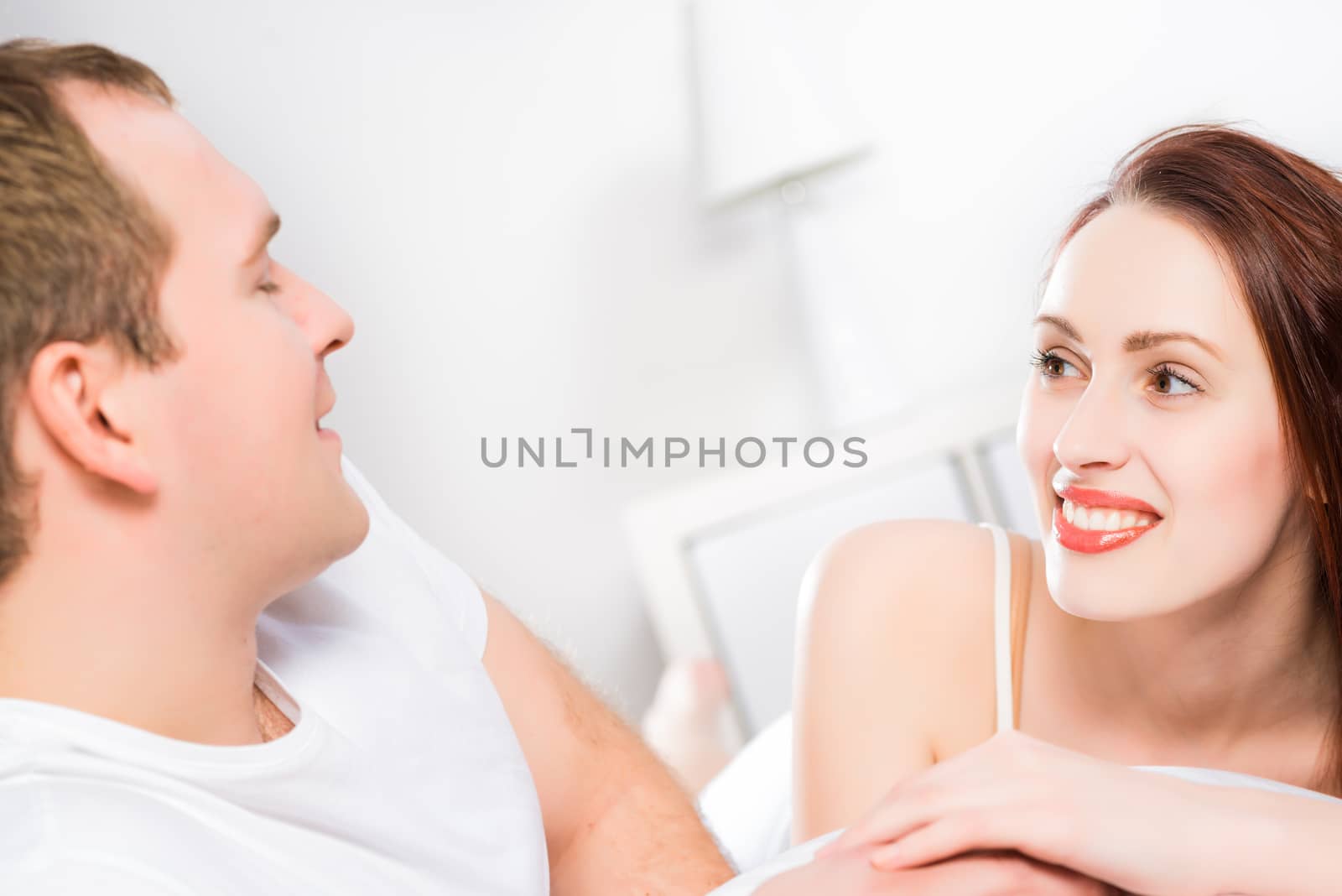 young beautiful woman lying in bed and looking at her husband