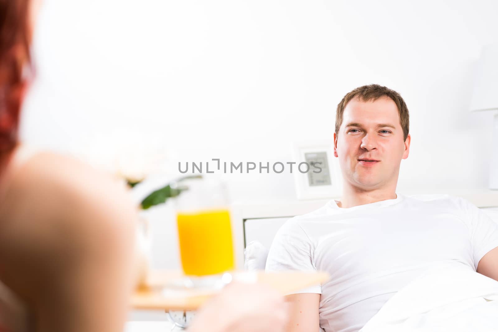 woman brought her boyfriend breakfast in bed, holding a tray of juice and breakfast