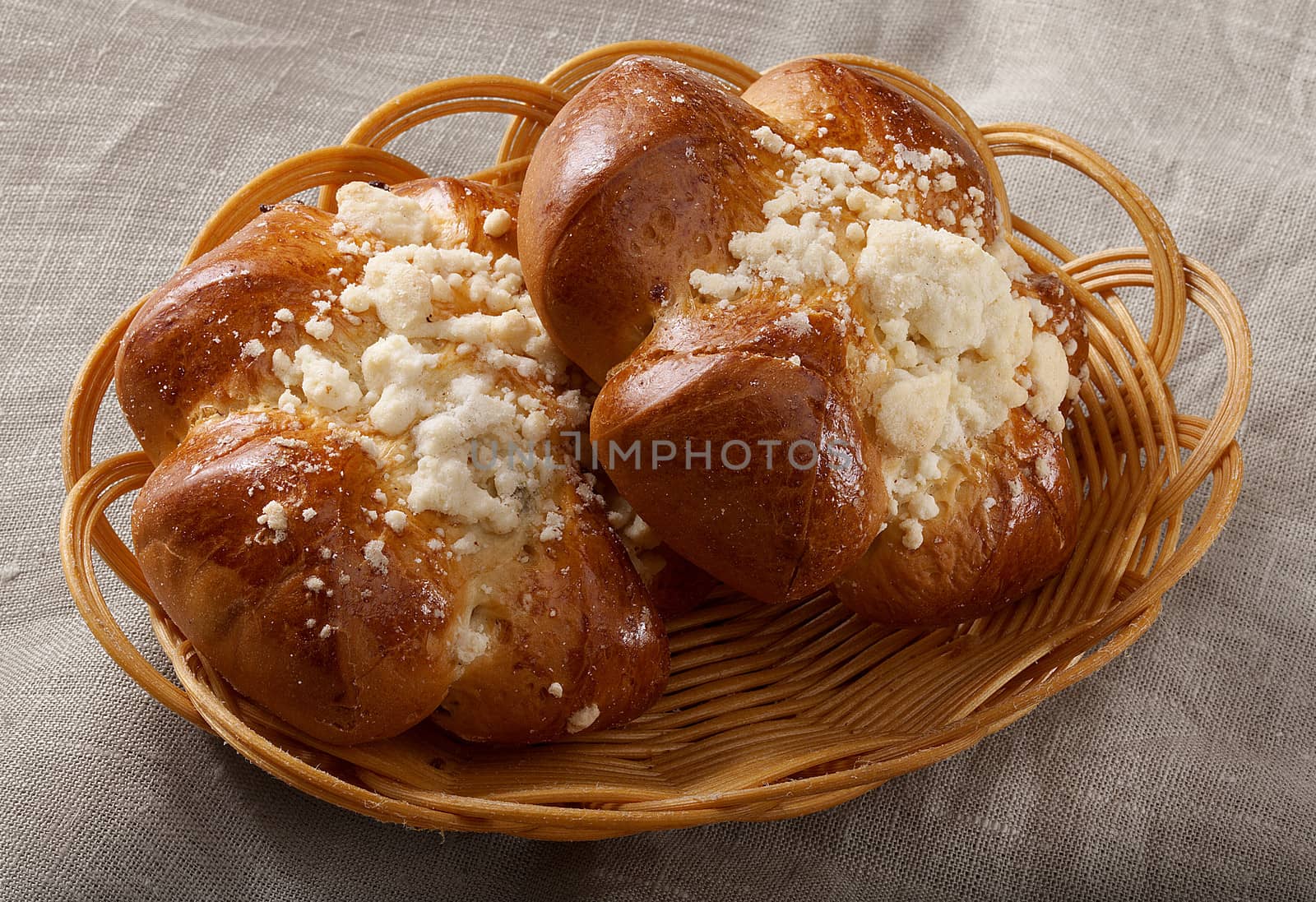 Two buns in the bread-basket on the tablecloth