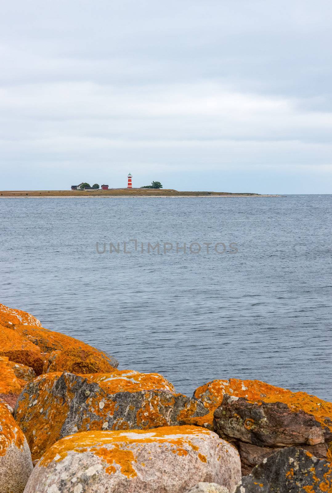 Orange stones on the coastline of Gotland, Sweden. Lighthouse on the other shore.