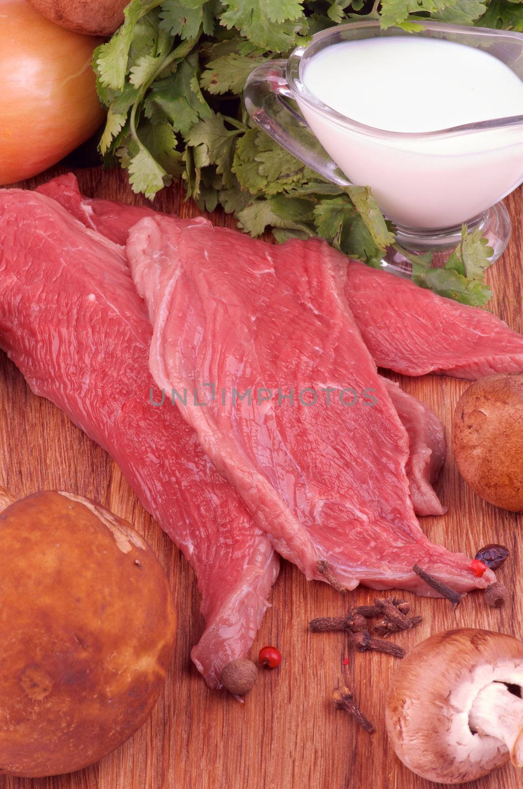 Cooking Beef Stroganoff. Arrangement of Ingredients with Raw Beef, Fresh Edible Mushrooms, Onion, Spices, Greens and Milk closeup on Wooden background