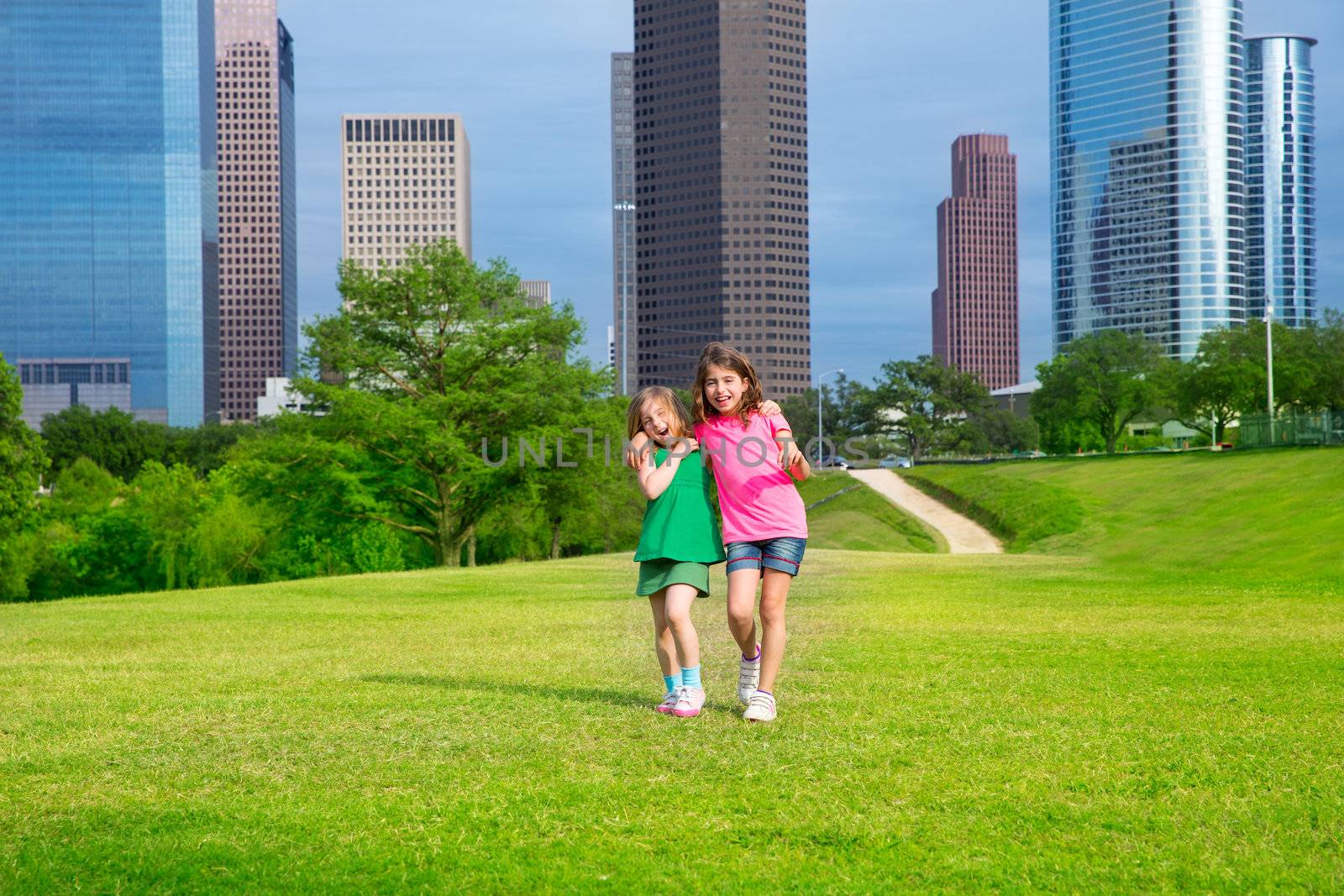 Two sister girls friends walking in urban modern skyline on park lawn