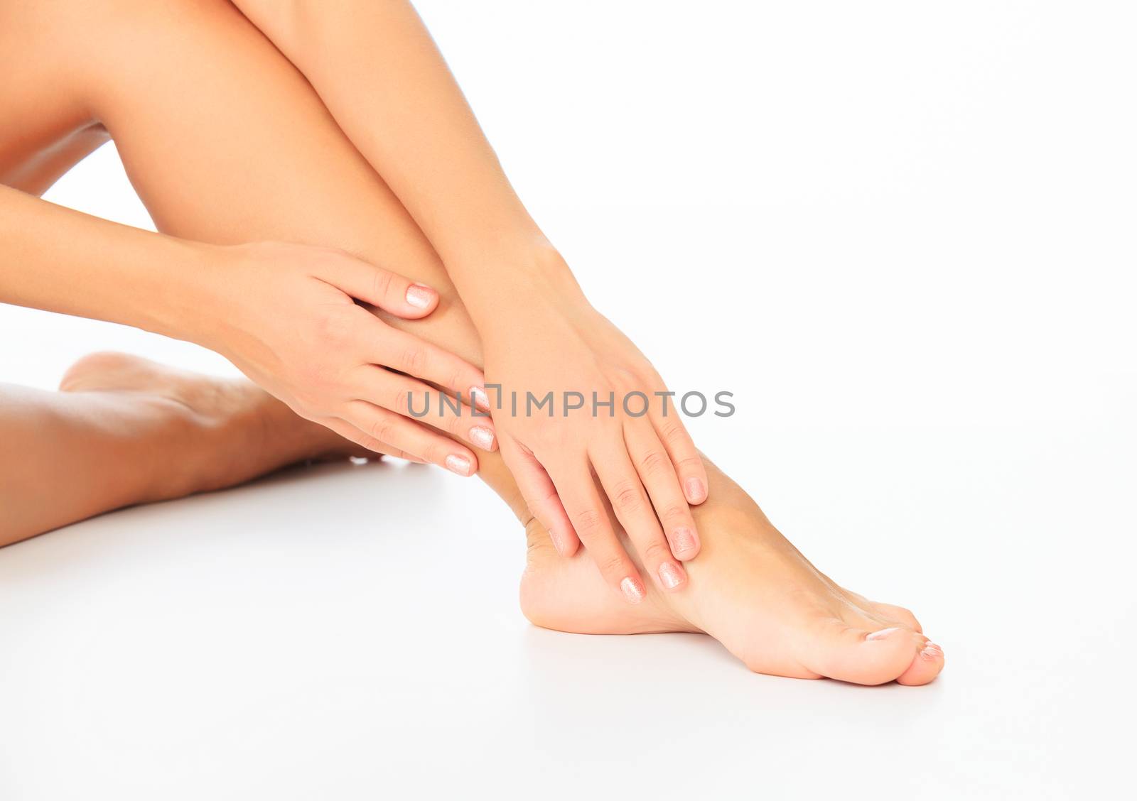 Woman touches her leg, white background, copyspace. by Nobilior