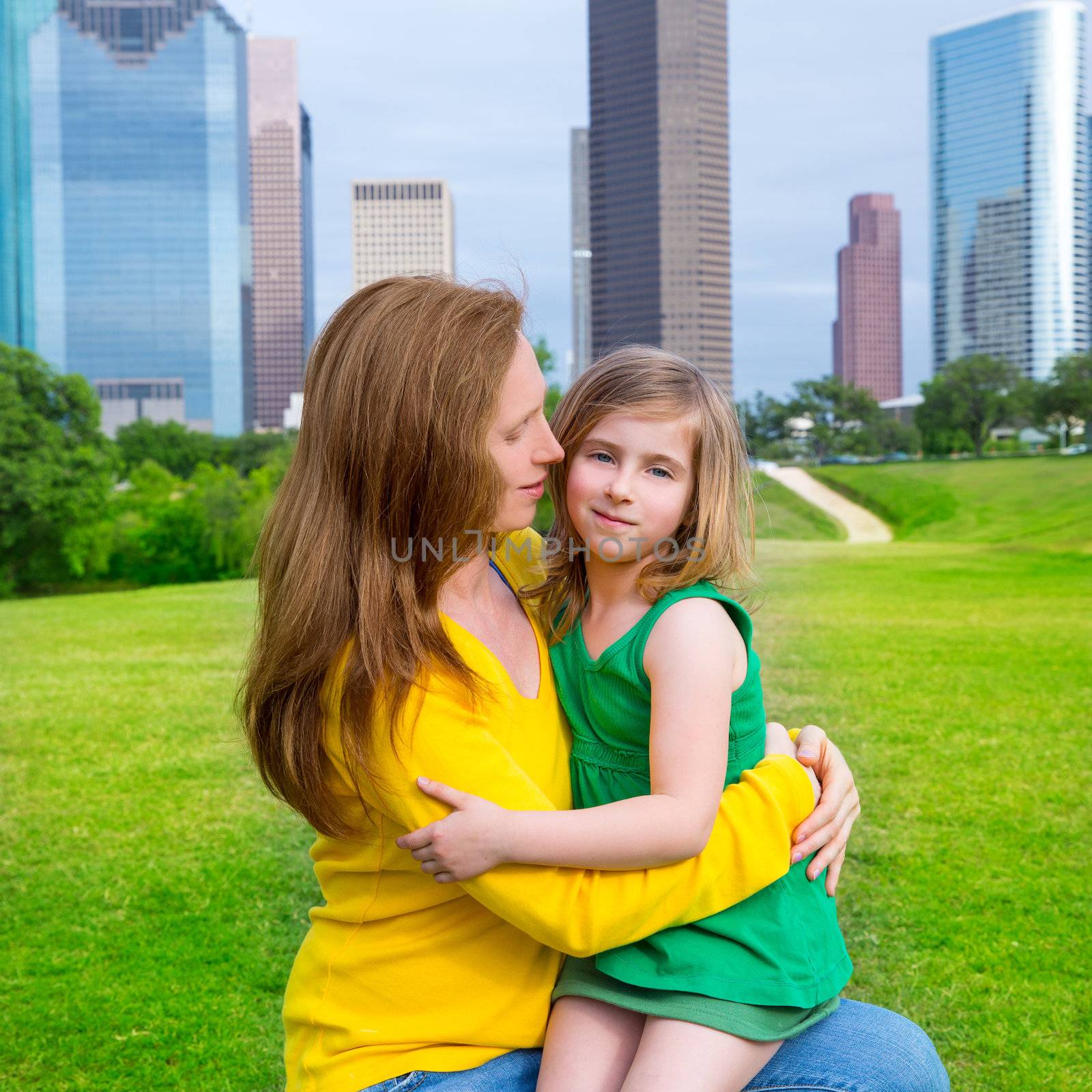 Mother and daughter happy hug in park at city skyline by lunamarina