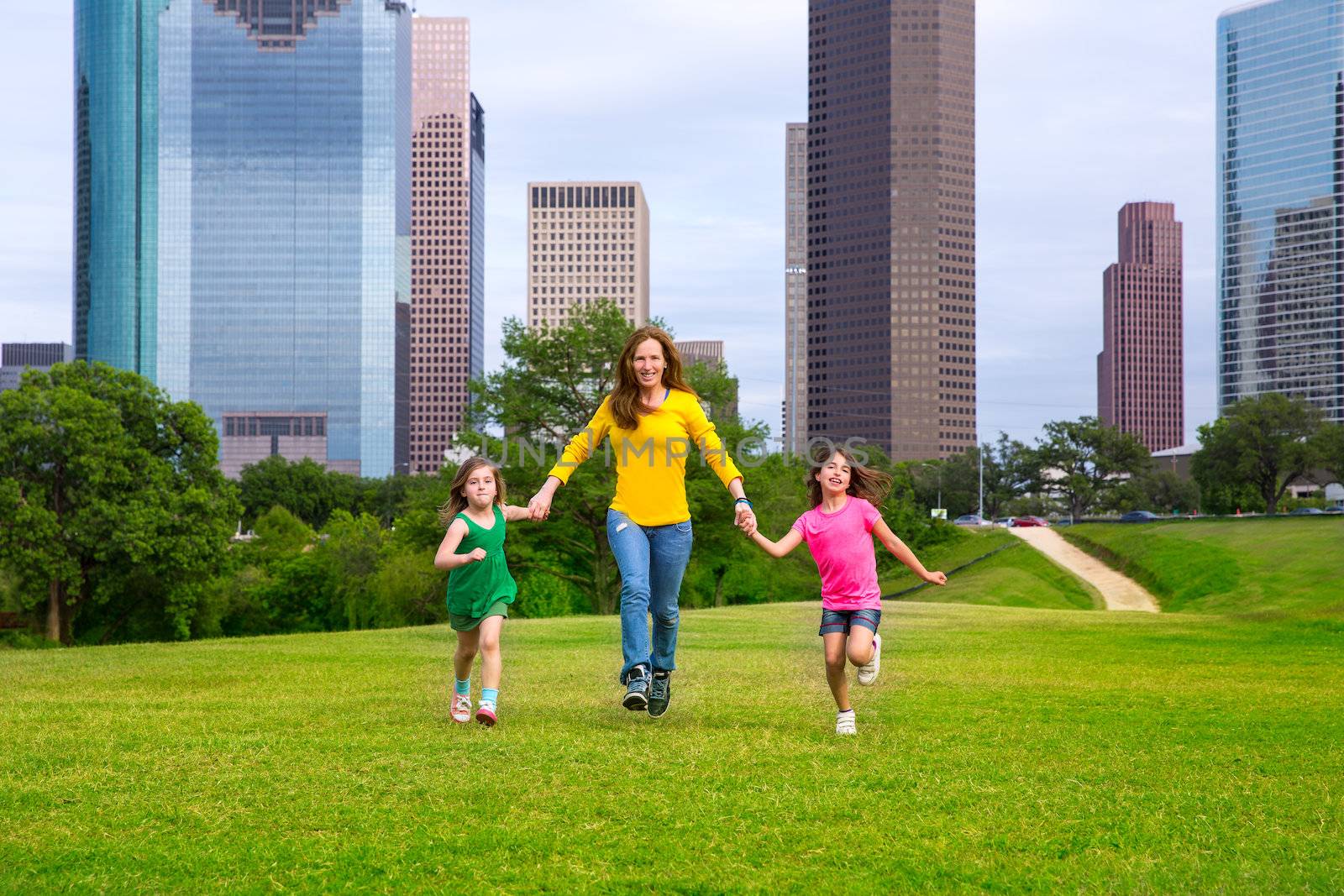 Mother and daughters walking holding hands on city skyline by lunamarina