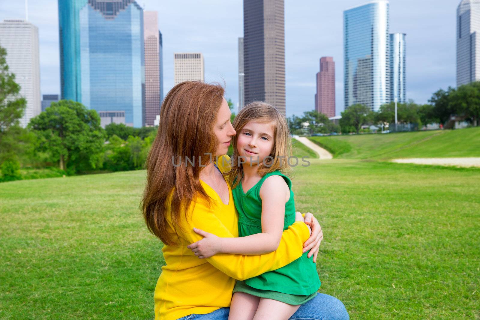 Mother and daughter happy hug in park at city skyline by lunamarina