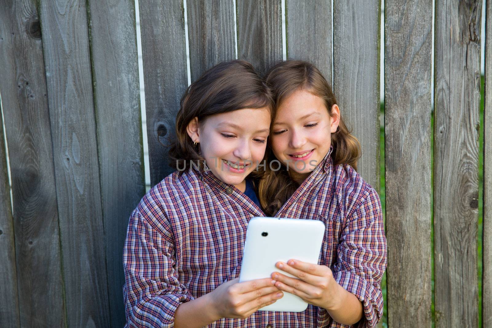 twin girls fancy dressed up pretending be siamese with dad shirt playing with tablet pc