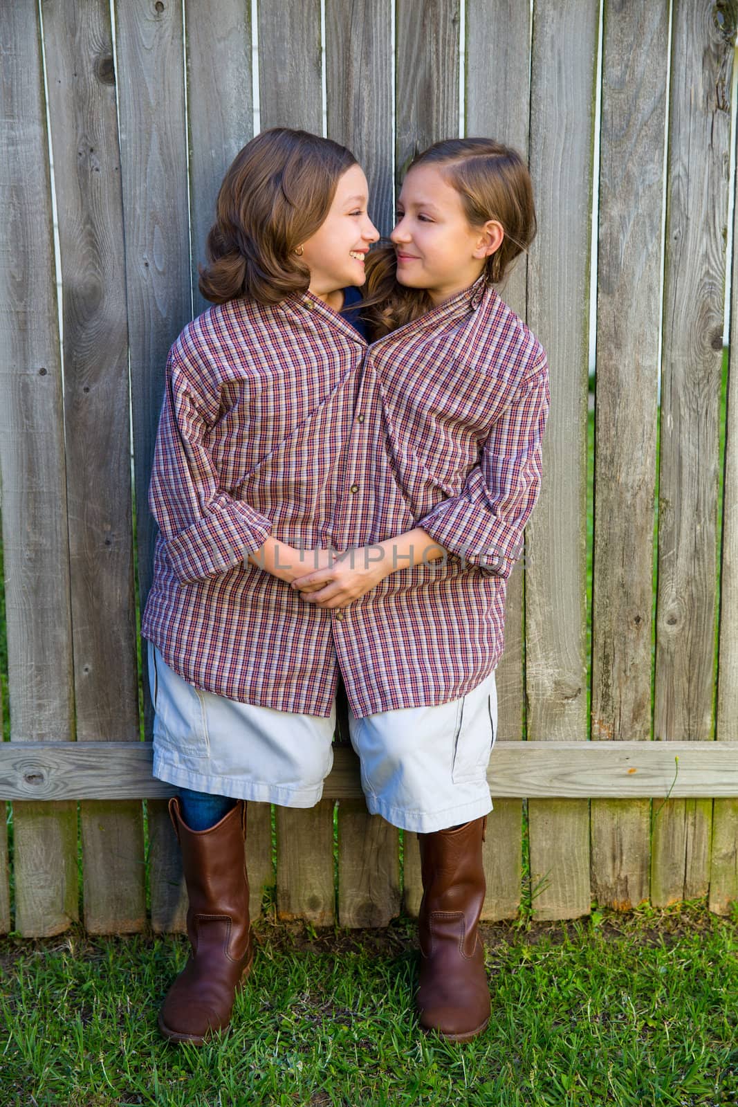 twin girls fancy dressed up pretending be siamese with his father shirt looking eachother