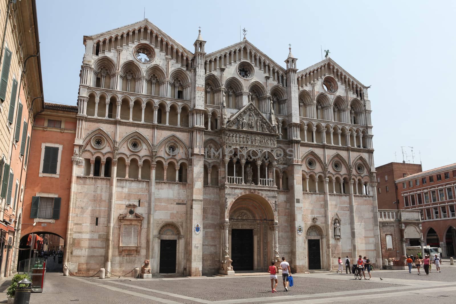 Ferrara, Italy – July 17, 2013; Front view of the Ferrara Cathedral on the main square in Ferrara, Italy, with tourists passing by.