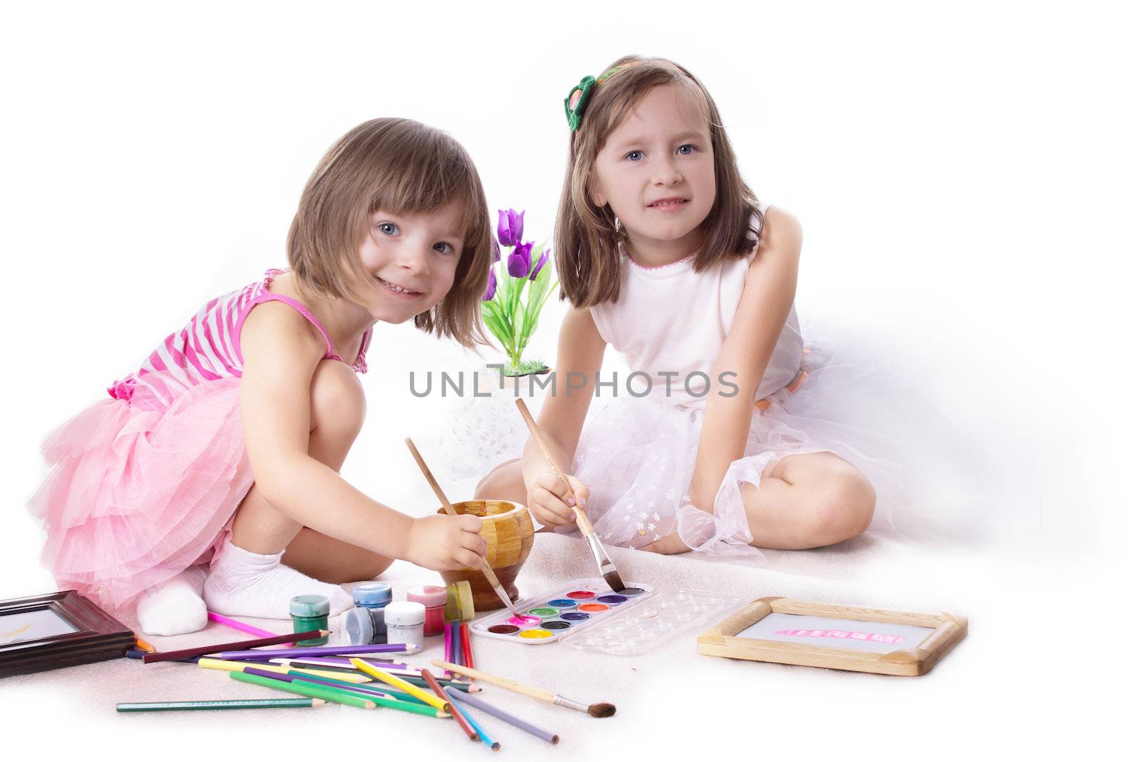 Two little girls drawing with paint on white