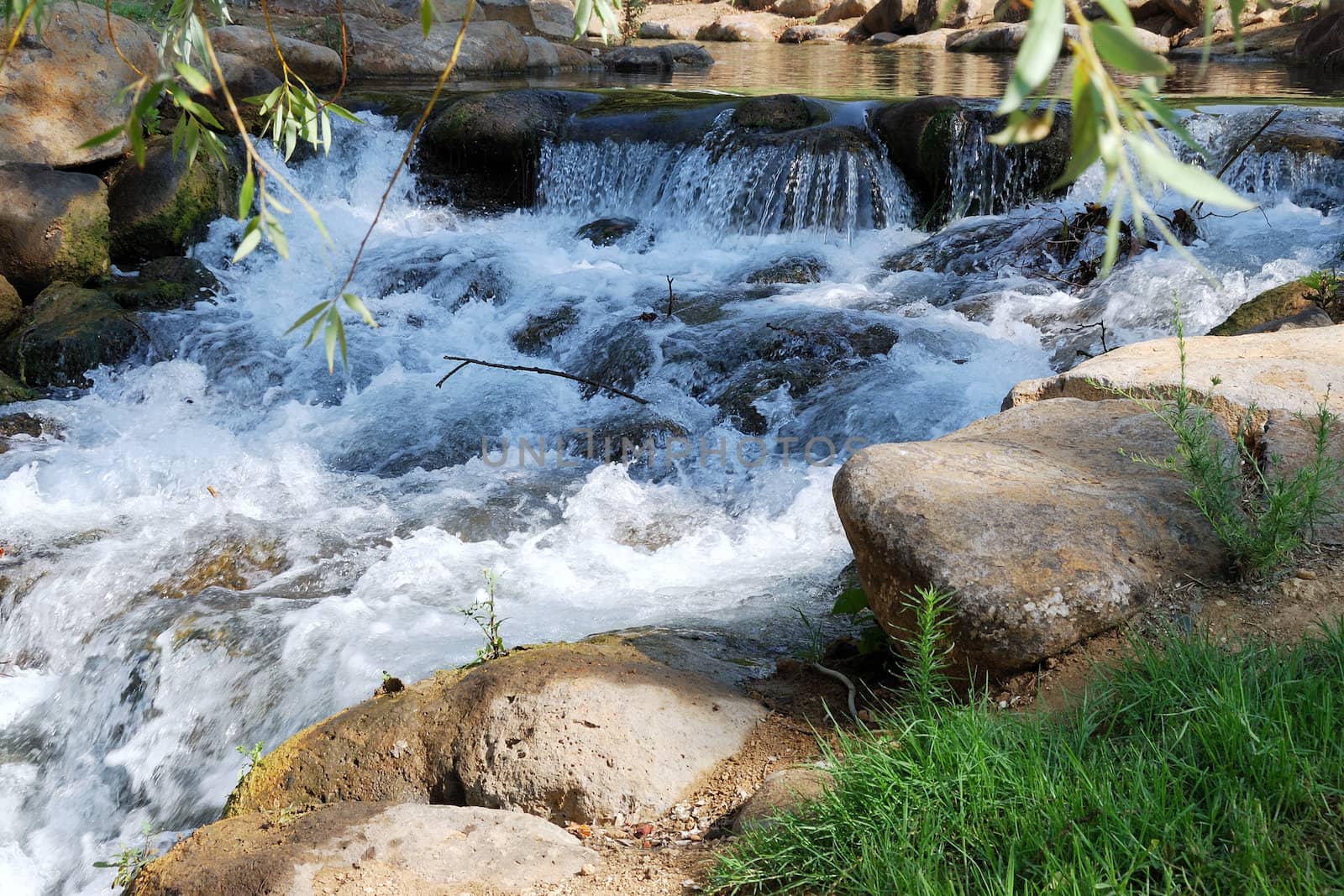 The small mountain river with waterfalls in the sunny day