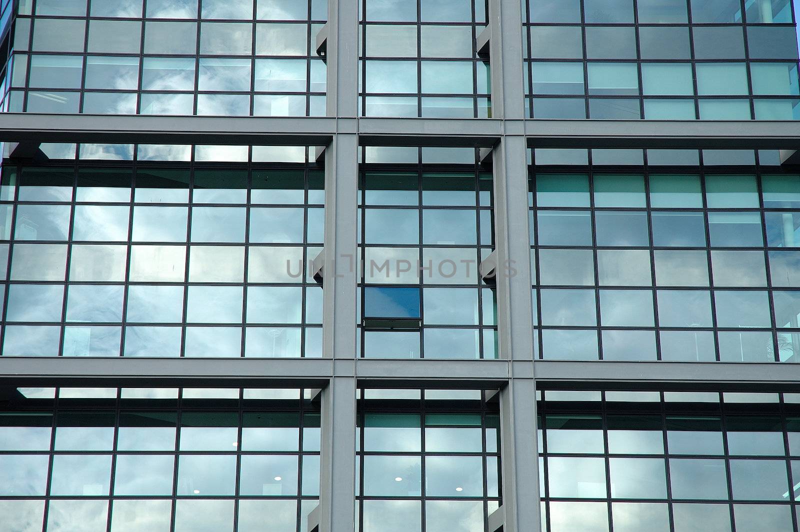 Windows of modern office building reflecting clouds