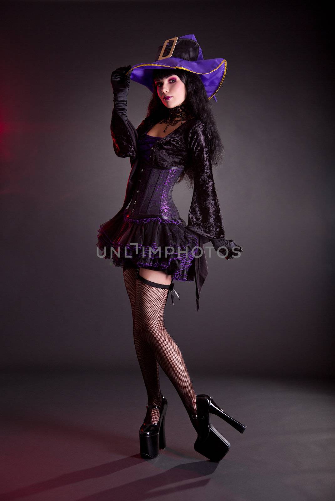 Pretty witch in purple and black gothic fantasy Halloween costume, full length shot  