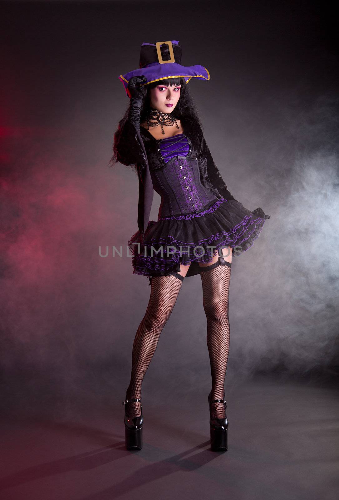 Sexy witch in purple and black gothic fantasy Halloween costume, full length shot  