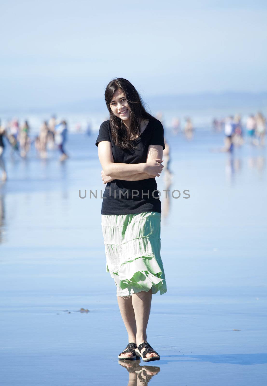 Beautiful biracial young woman or teen enjoying walk along beach by Pacific Ocean