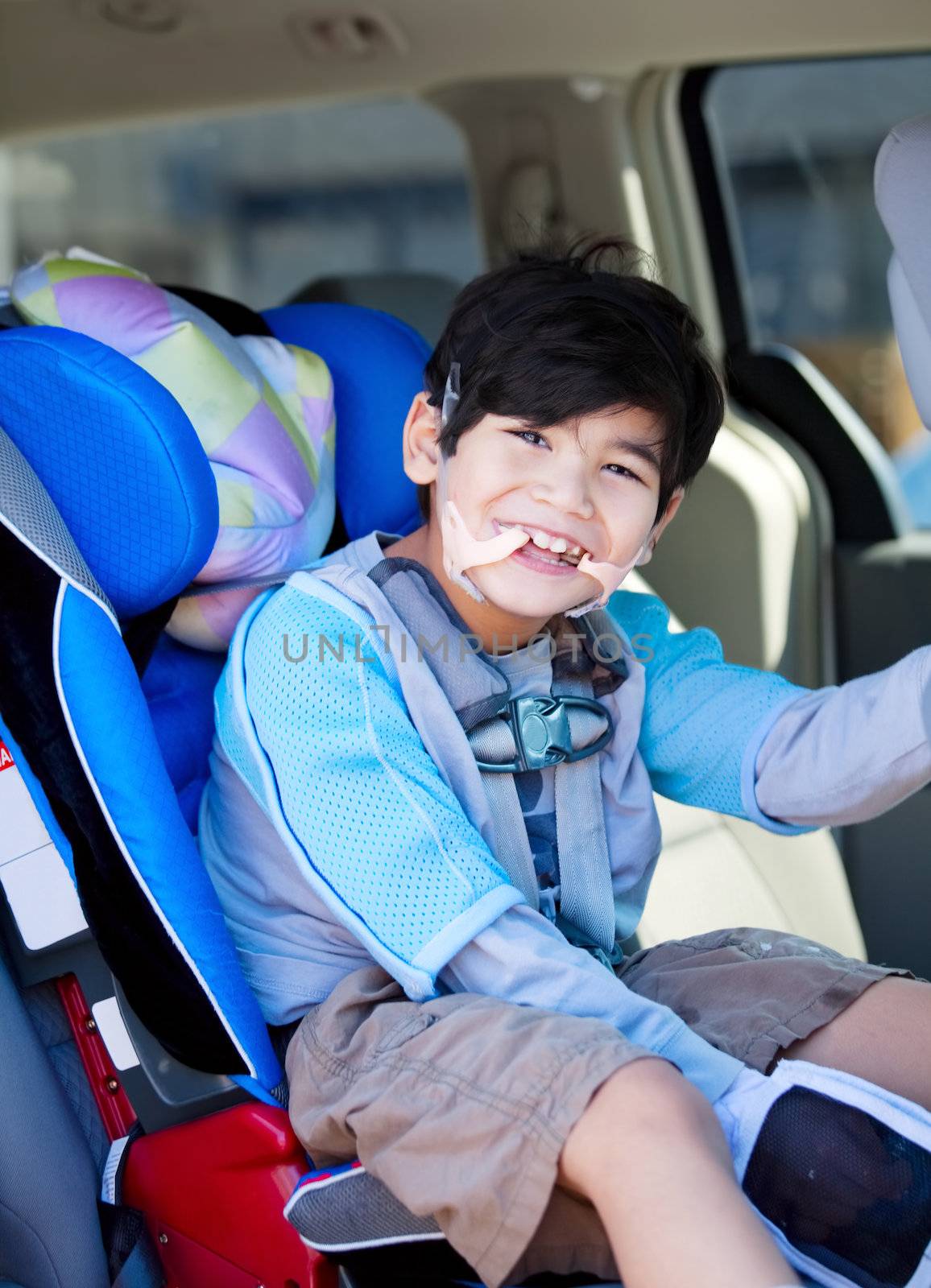 Handsome disabled six year old boy smiling in carseat