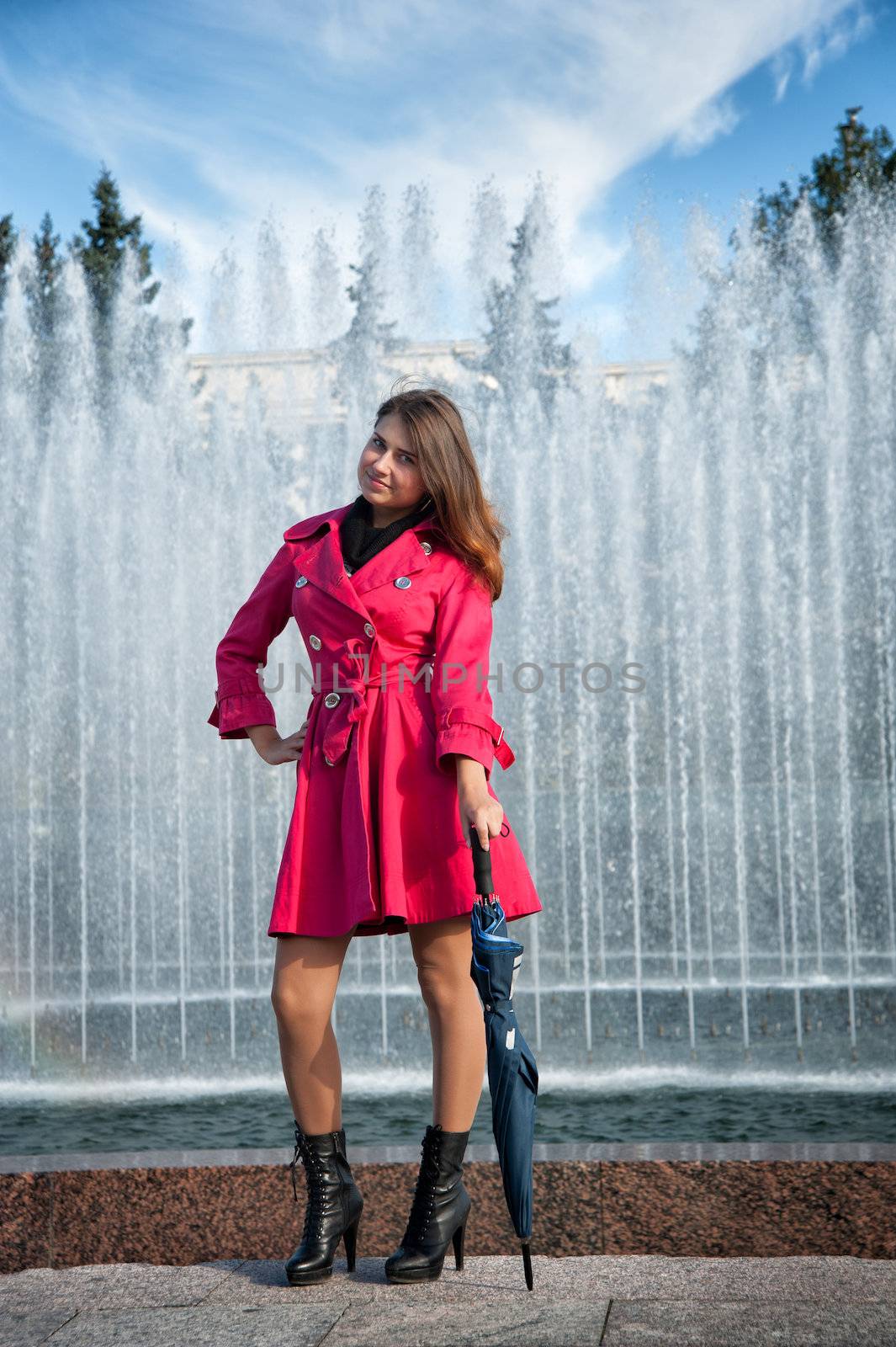 happy young woman in a red raincoat with an umbrella