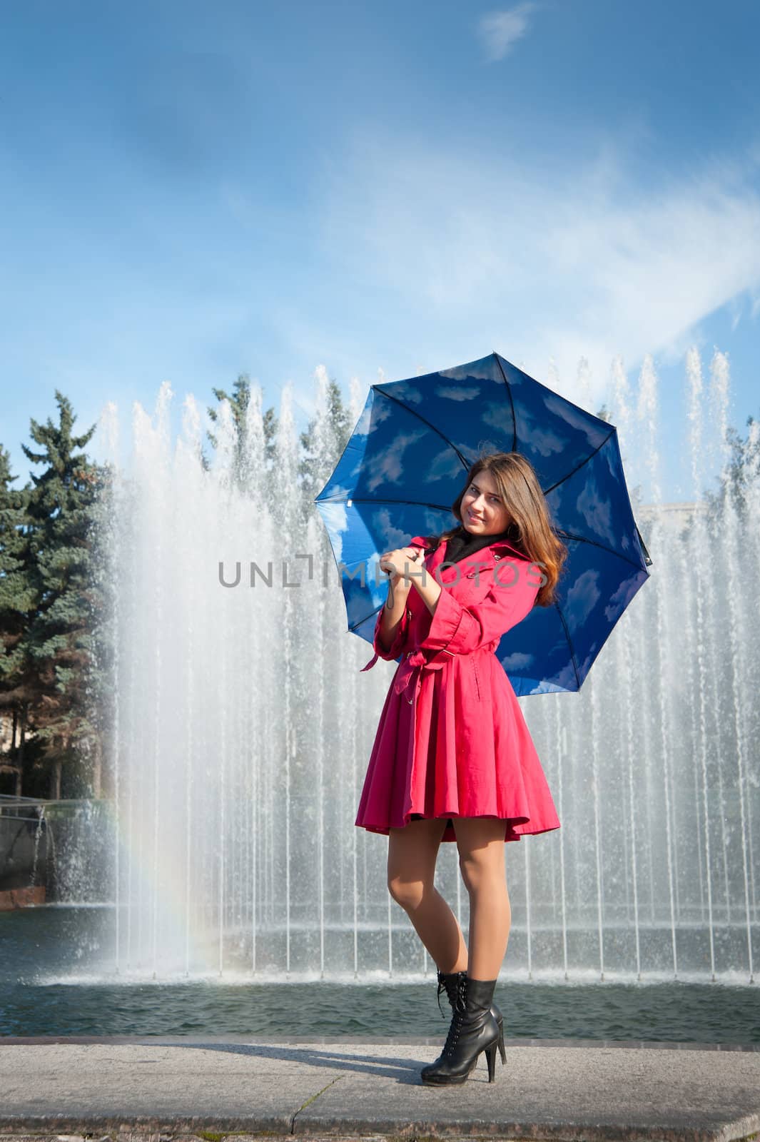 happy young woman in a red raincoat with an umbrella