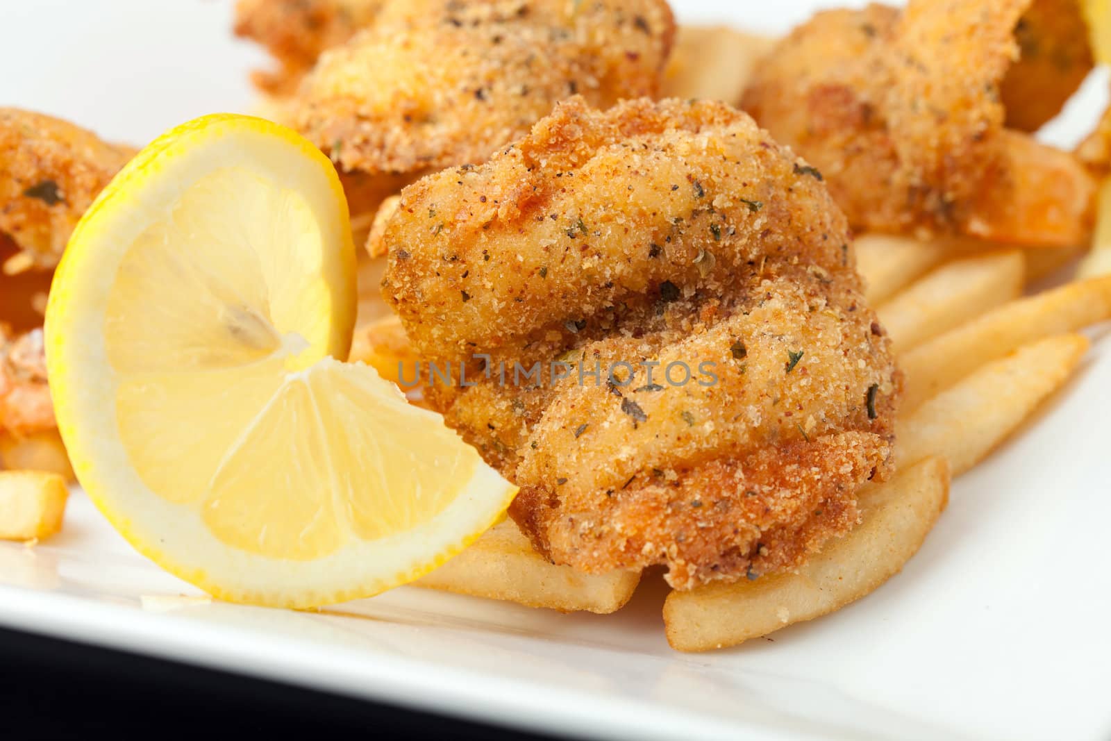 Fried shrimp and french fries plate garnished with lemon.