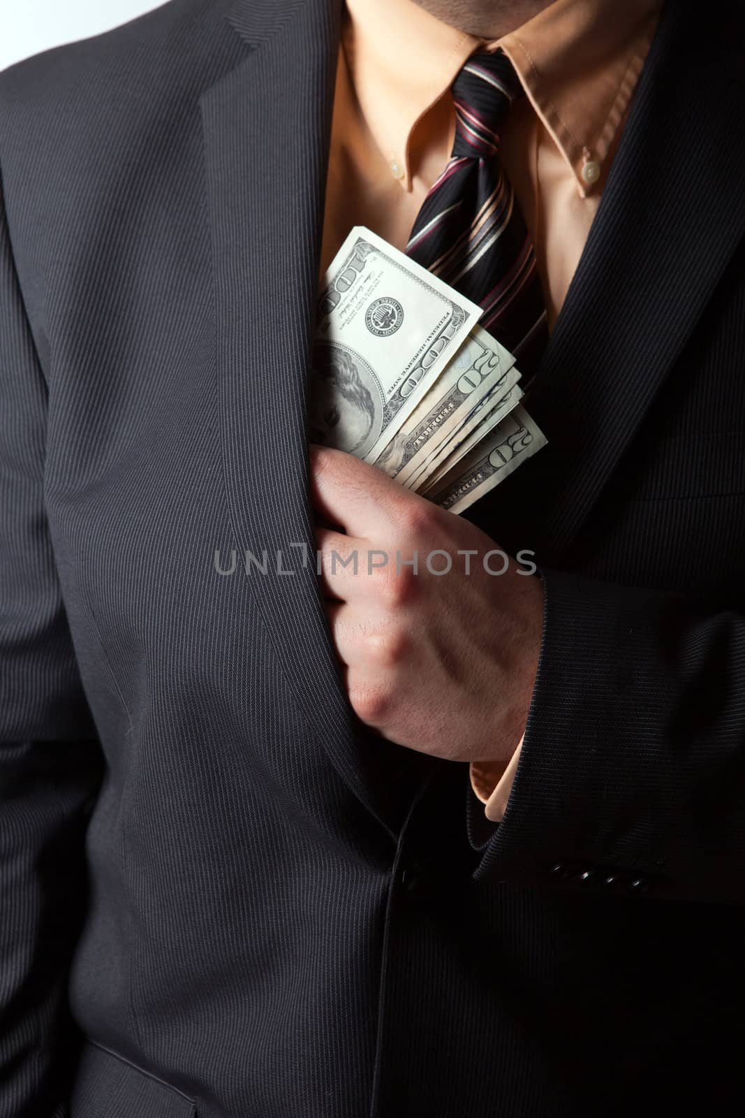 Close up of a business mans hand hiding money in his suit jacket pocket.