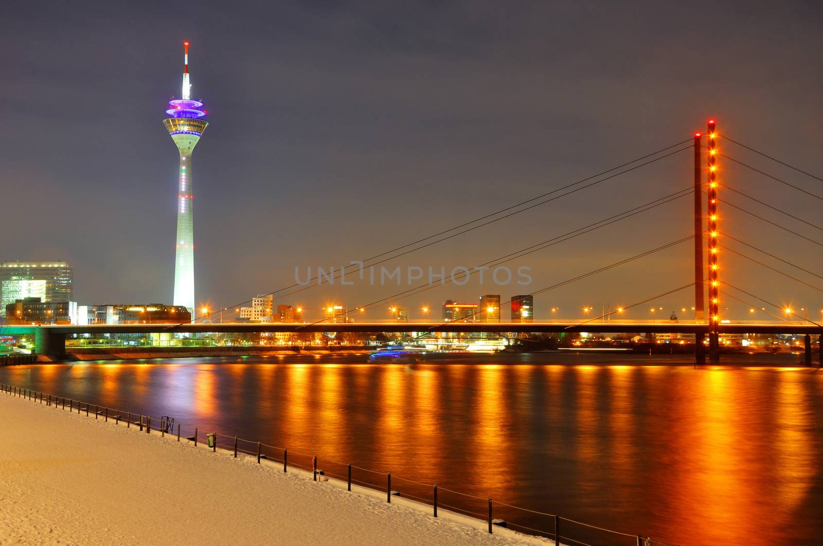Beautiful night shore of Rhein river at night in Dusseldorf with a Rheinturm tower and a bridge, Nordrhein-Westfalen, Germany