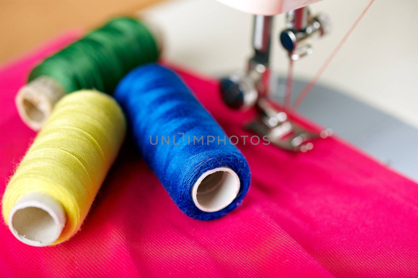 Close up of threads on fabric and sewing machine. Shalow DOF. Selective focus. Focus on blue threads.