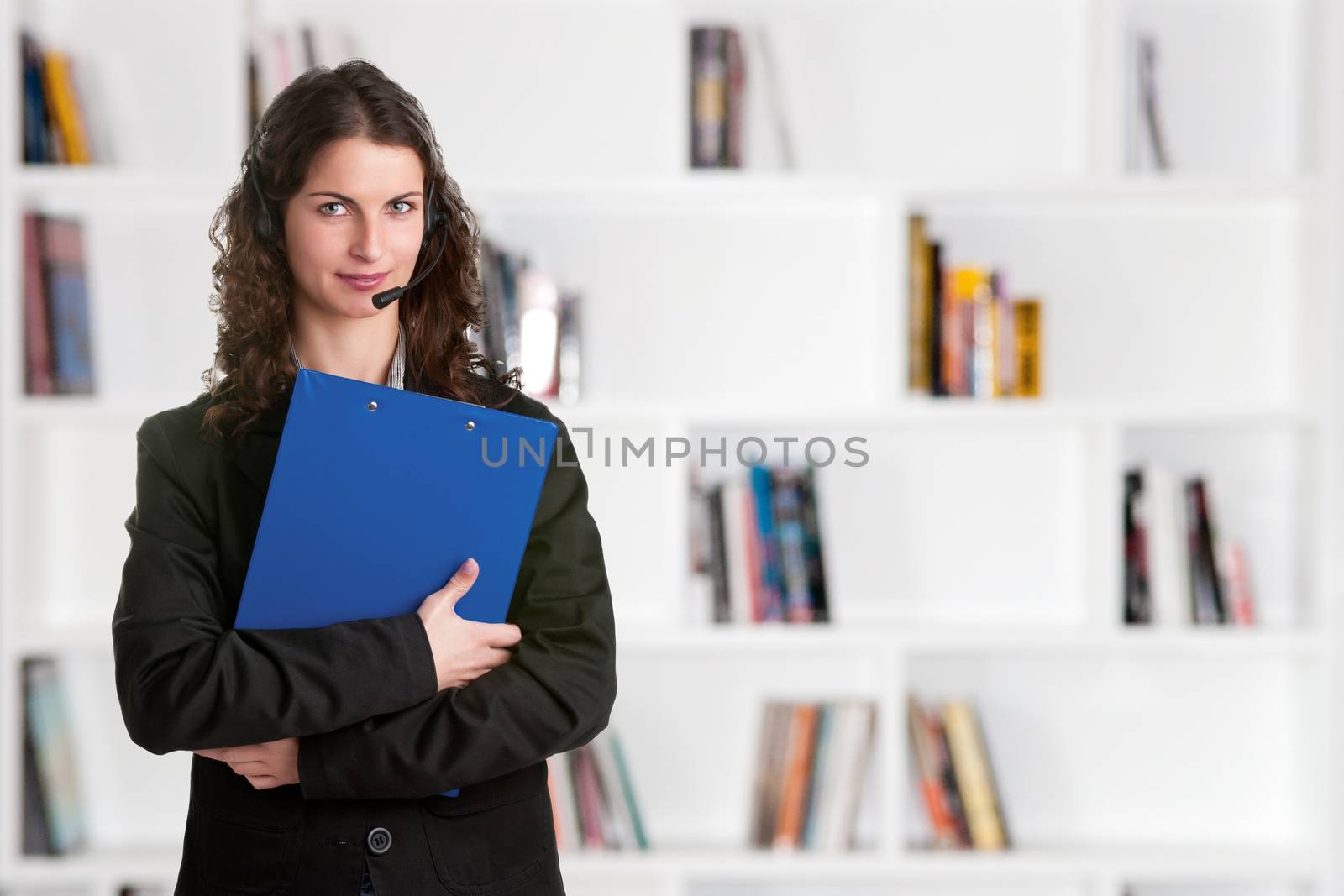 Corporate woman talking over her headset, holding a blue pad