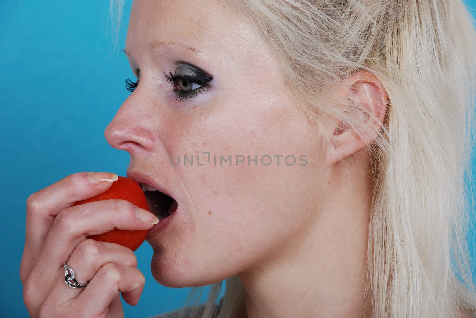 Blond womanl eating a tomato