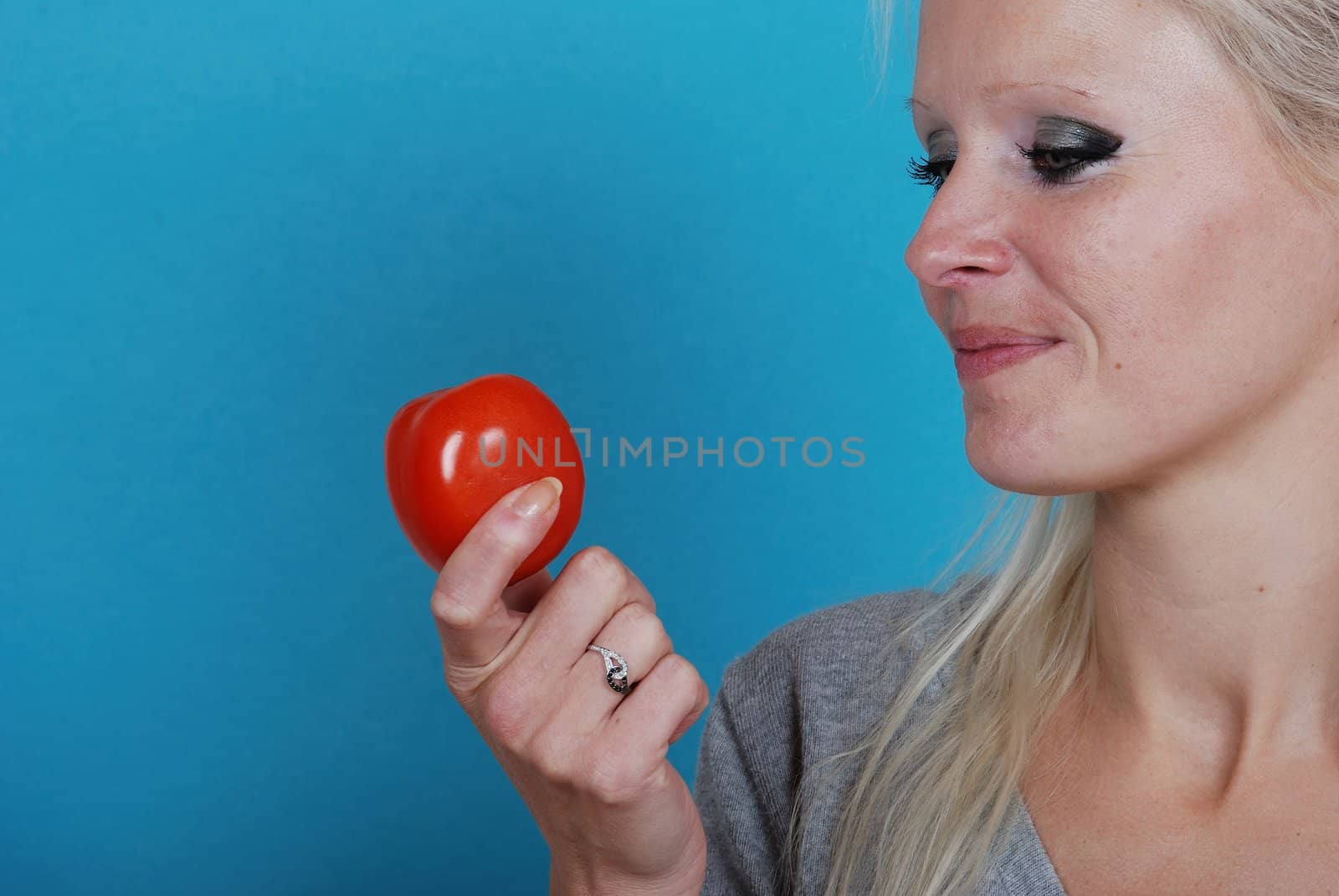 Blond womanl eating a tomato