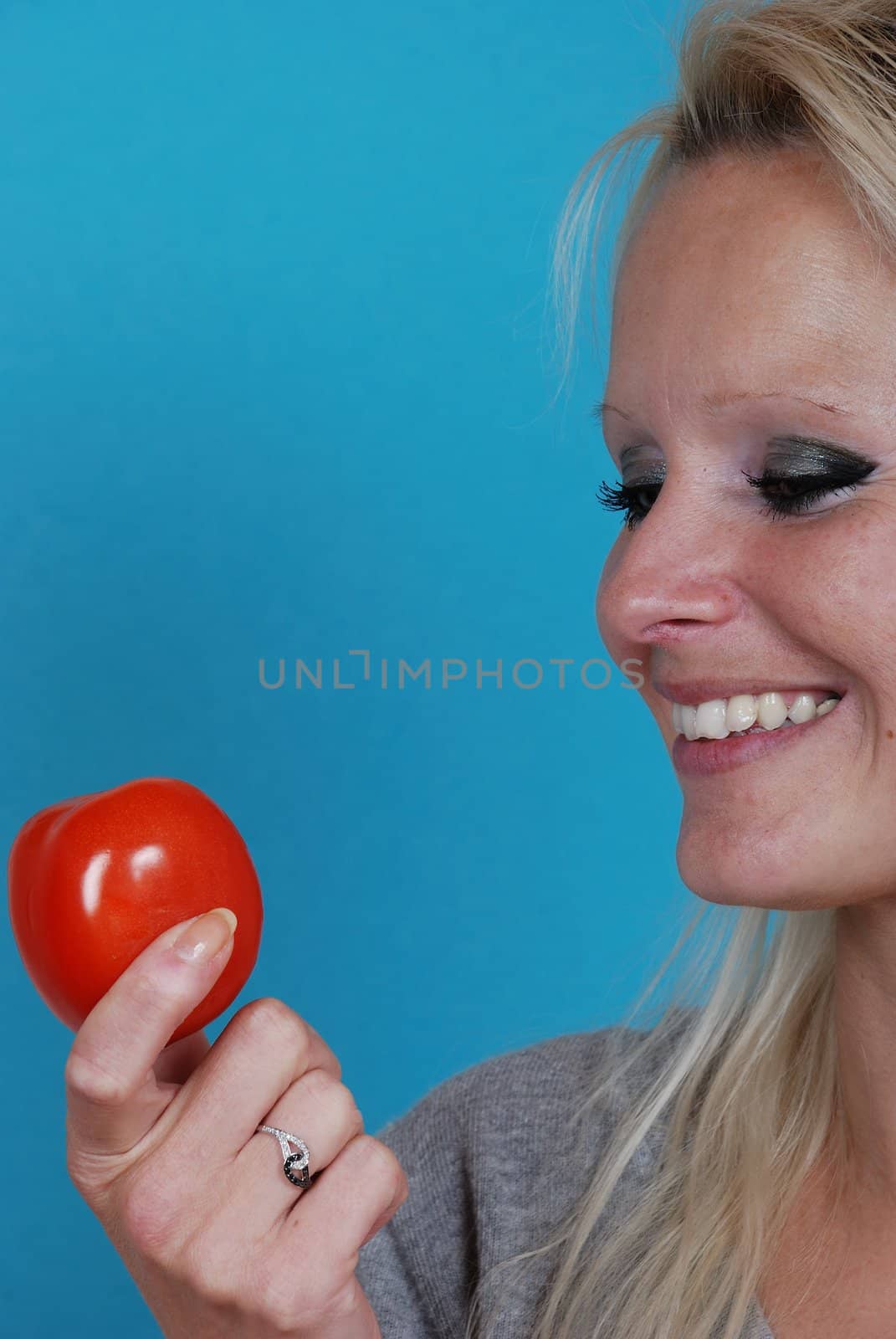 Blond womanl eating a tomato