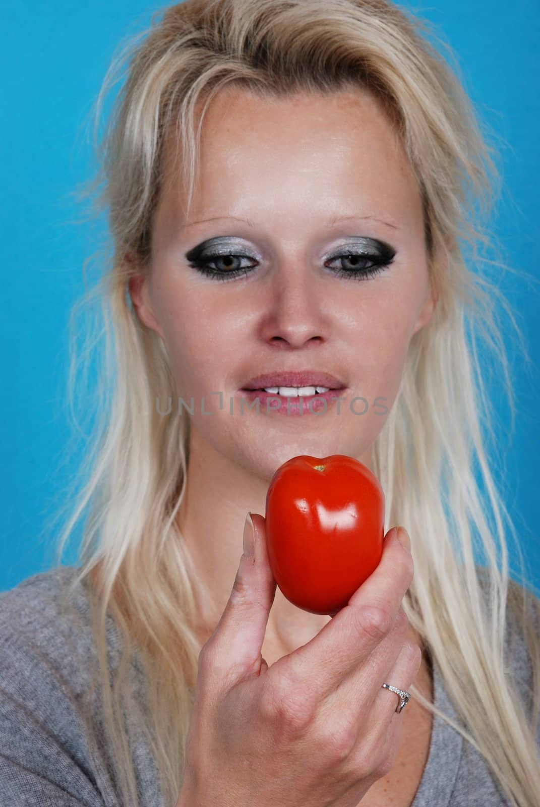 Blond womanl eating a tomato