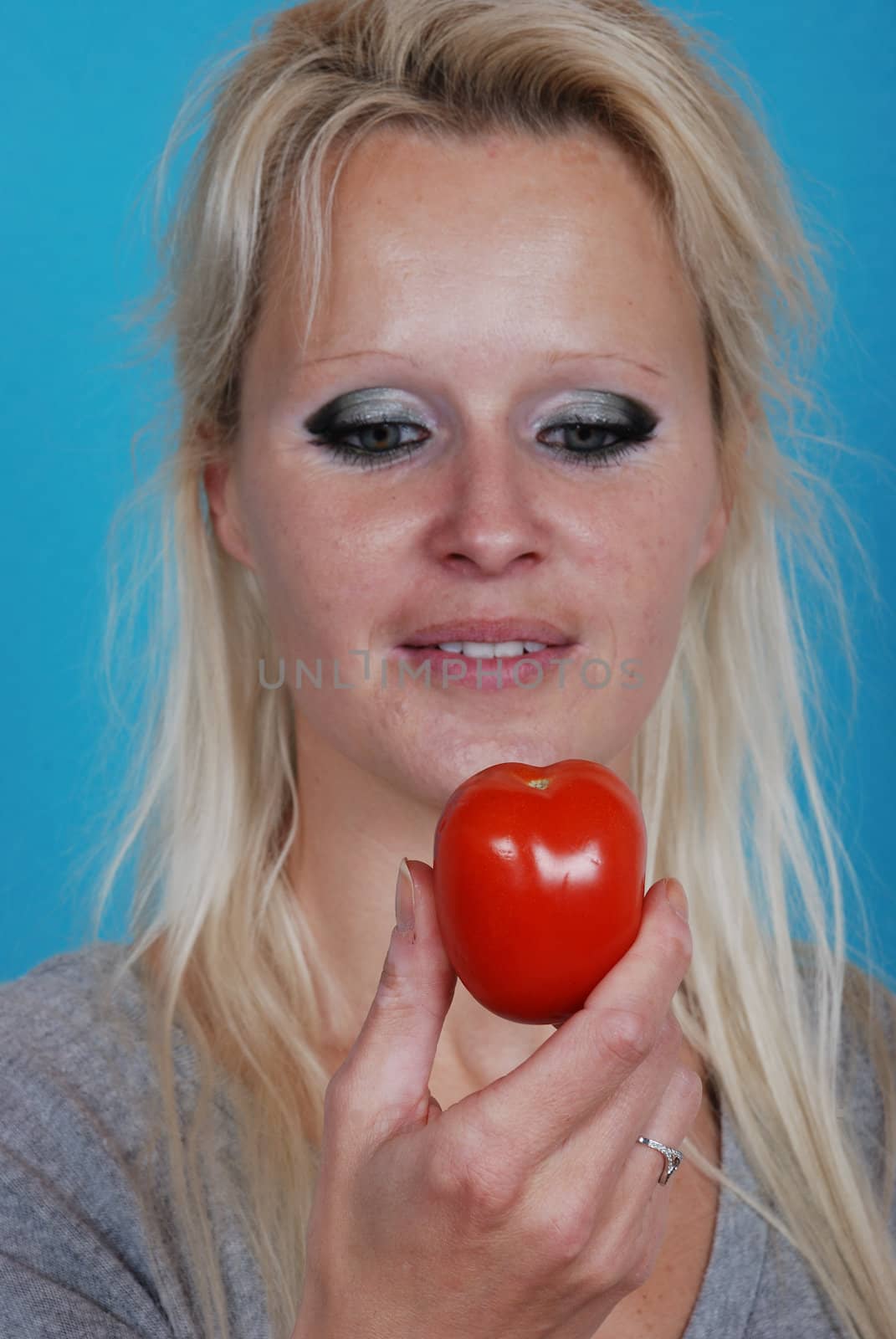 Blond womanl eating a tomato