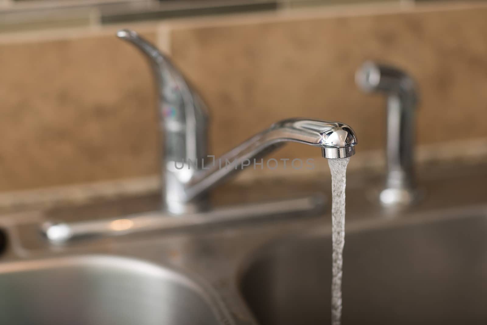 Water coming out of a faucet. View is a 3/4 view with shallow depth of field on the water coming out.