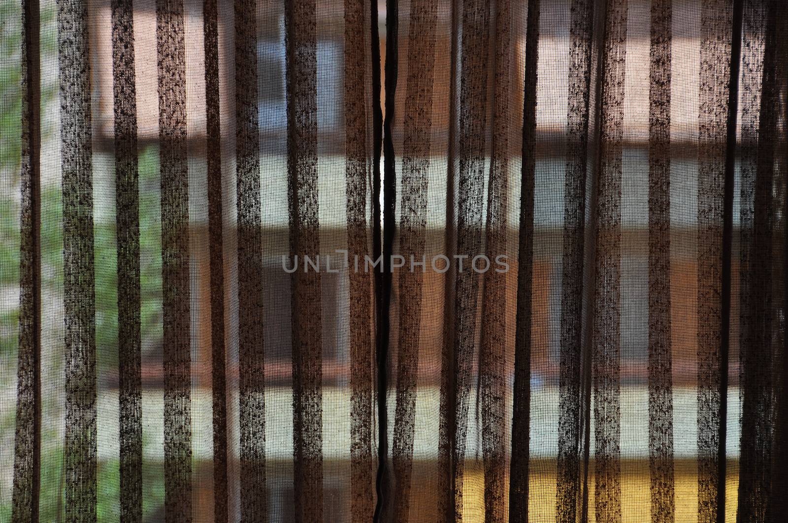 Brown transparent curtains and distorted colorful building in the background.