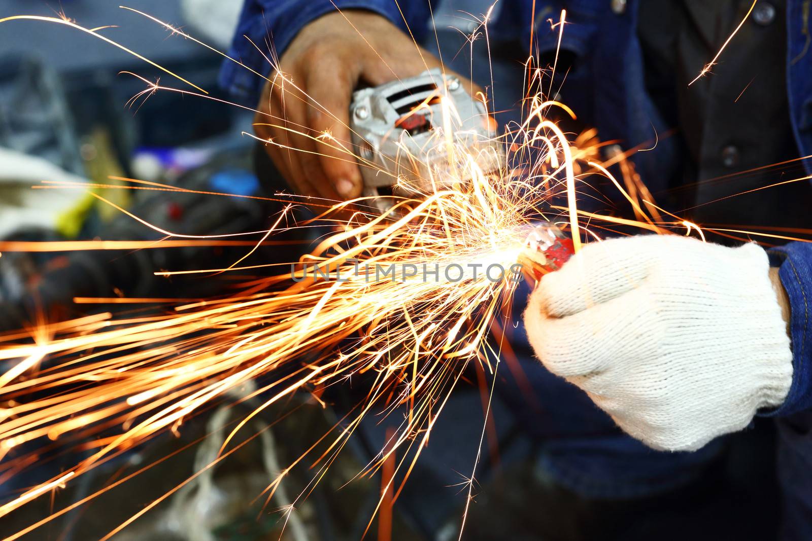 Worker grinding steel pipe with Electric Angle Grinder