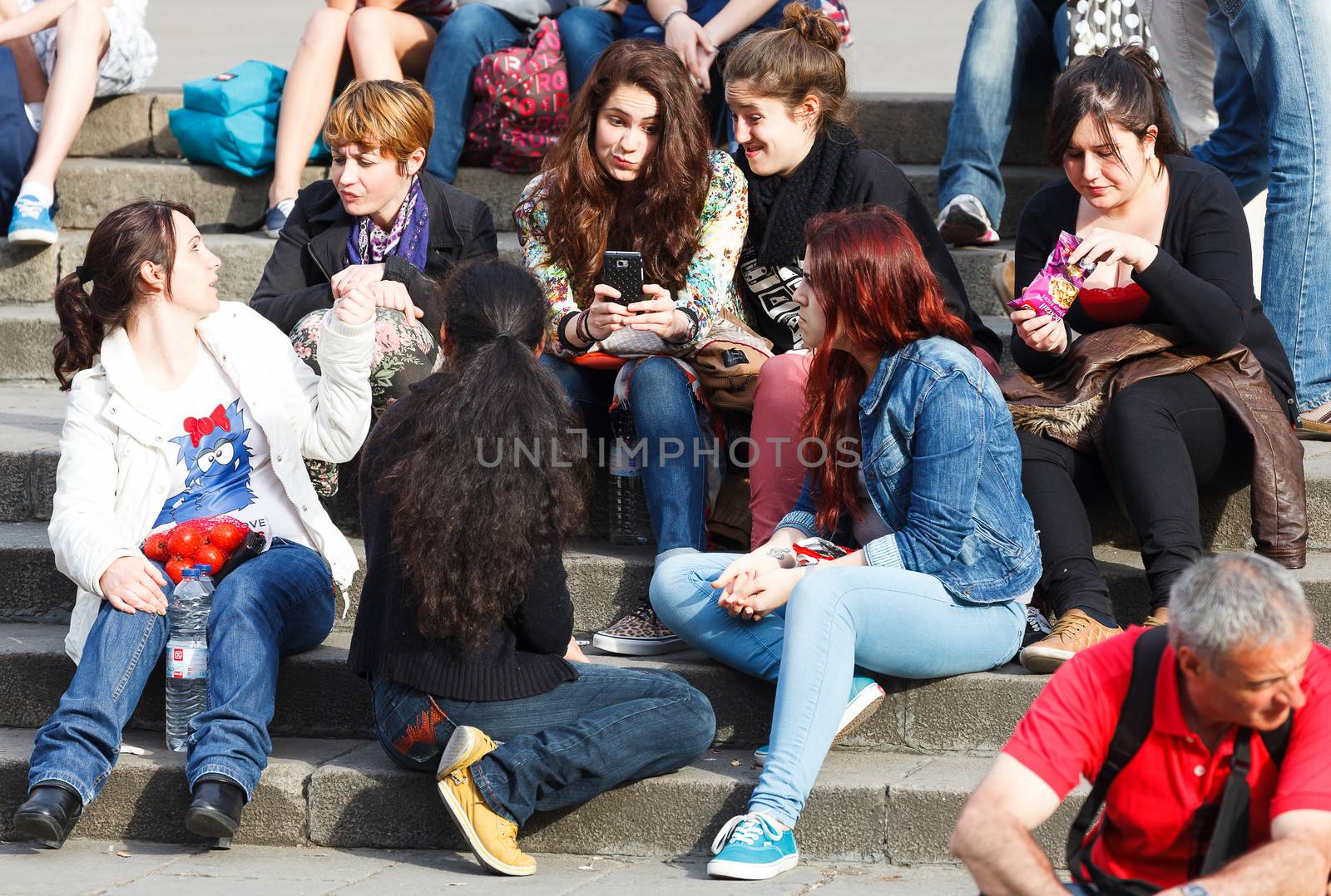 BARCELONA, SPAIN - APR 16: Company of young girls sitting on steps of Barcelona Cathedral. April 16, 2013 in Barcelona, Spain. This Cathedral, is the seat of the Archbishop of Barcelona