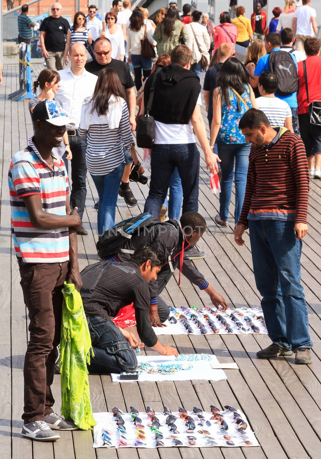 BARCELONA, SPAIN - APRIL 16 : Street market in port Vell on April 16, 2013 Barcelona. People buying and selling sunglasses, and souvenirs on the main pier of the port Vell, oldest port of Barcelona