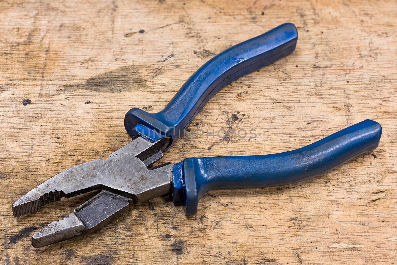 Old and dirty general purpose pliers on grunge wood table