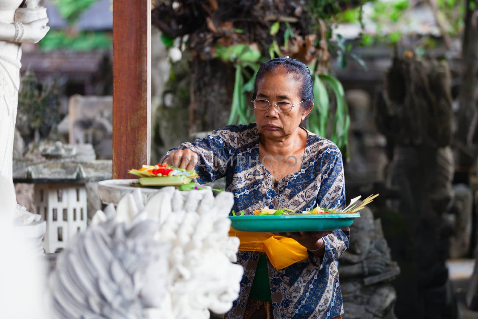 UBUD, BALI, INDONESIA - SEP 21: Woman puts balinese traditional offerings to gods on altar near main market on Sep 21, 2012 in Ubud, Bali, Indonesia