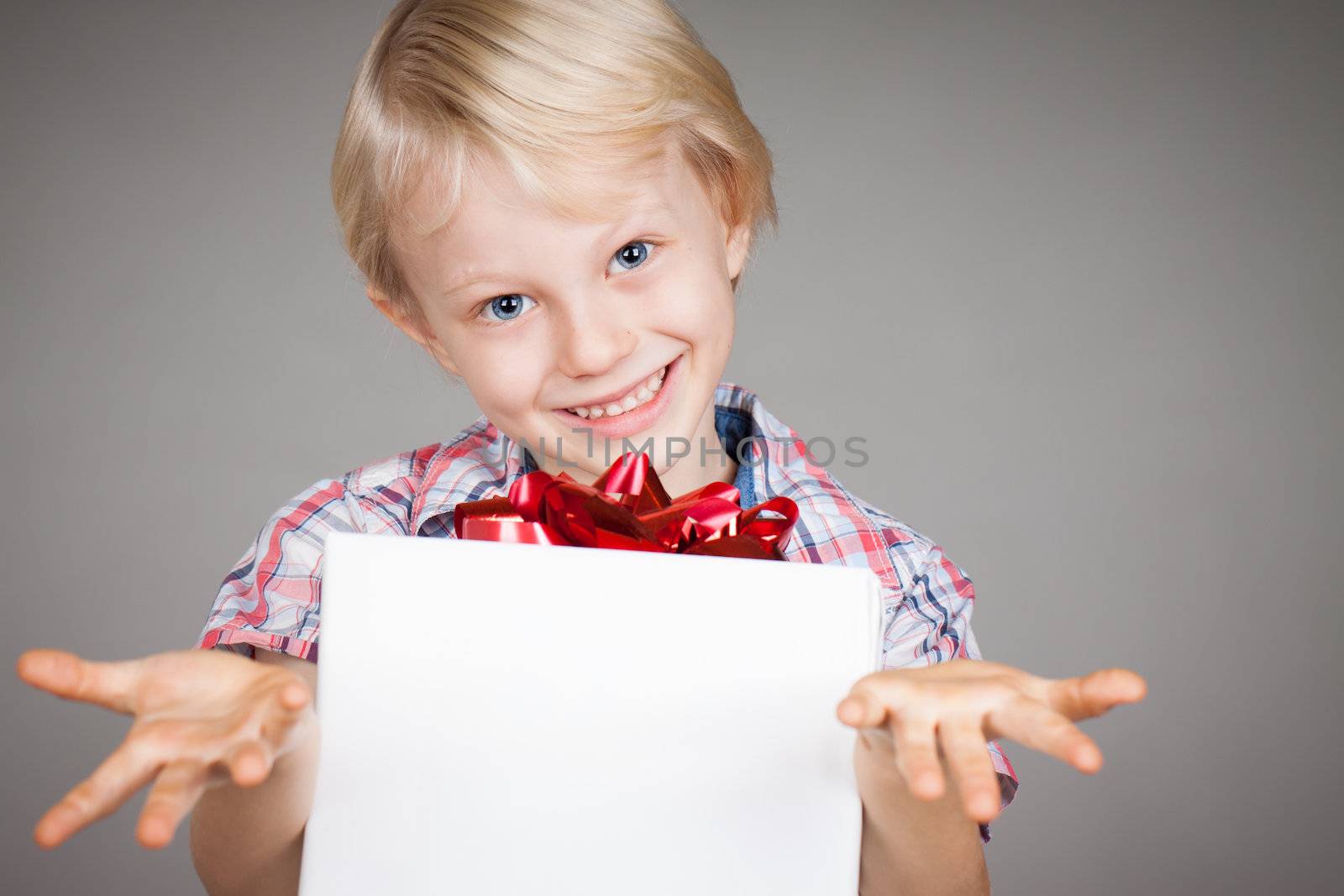 A very cute young boy giving a present and smiling at camera.