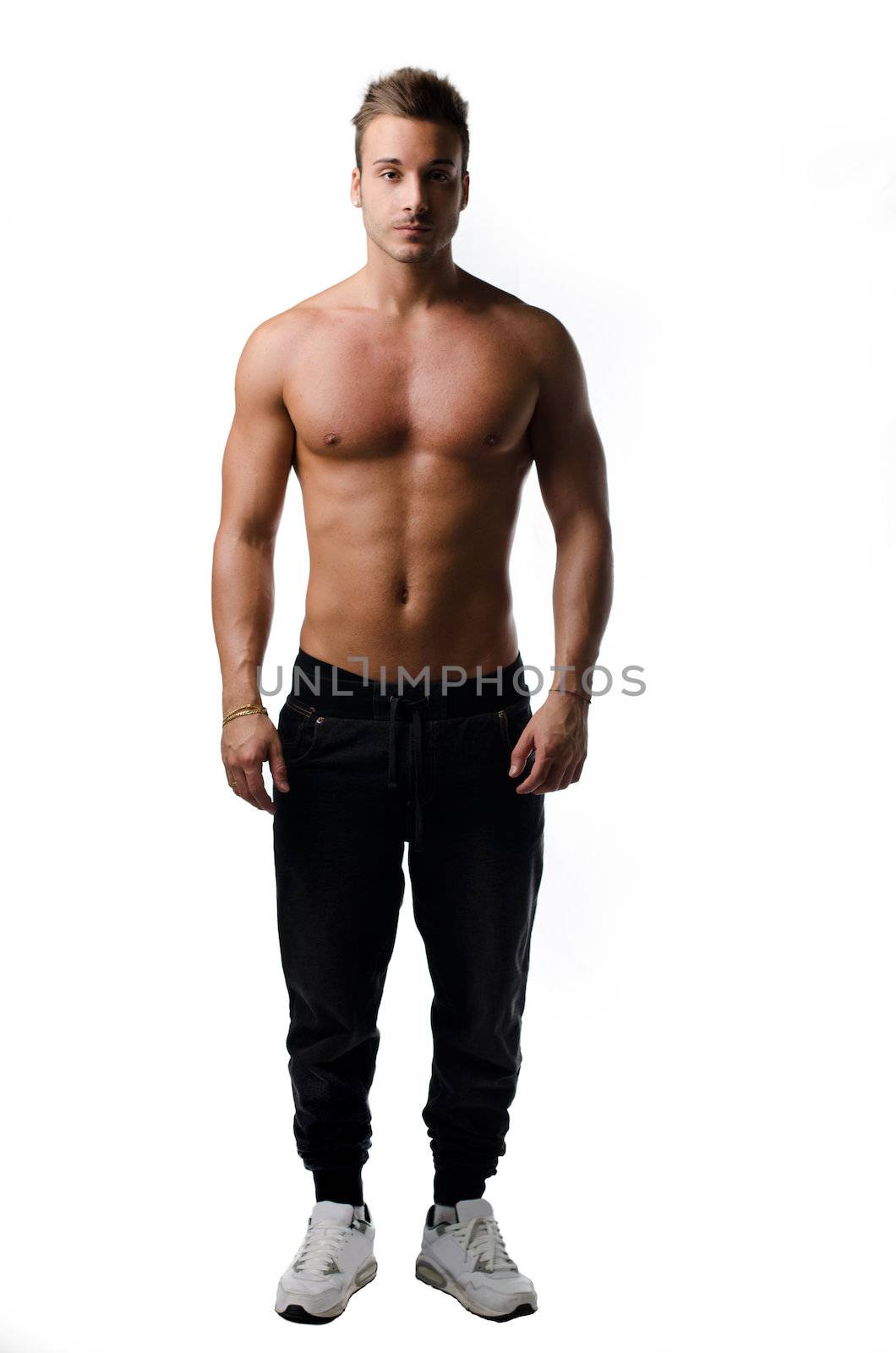 Full body shot of muscular young man standing and looking in camera, shirtless