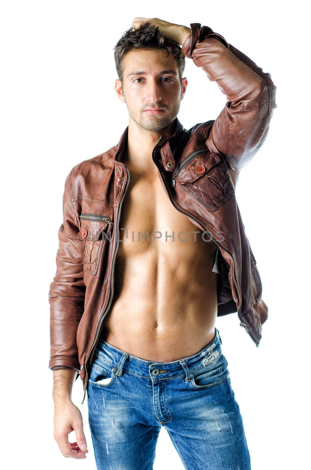 Attractive young man wearing leather jacket on naked torso and blue jeans, isolated on white