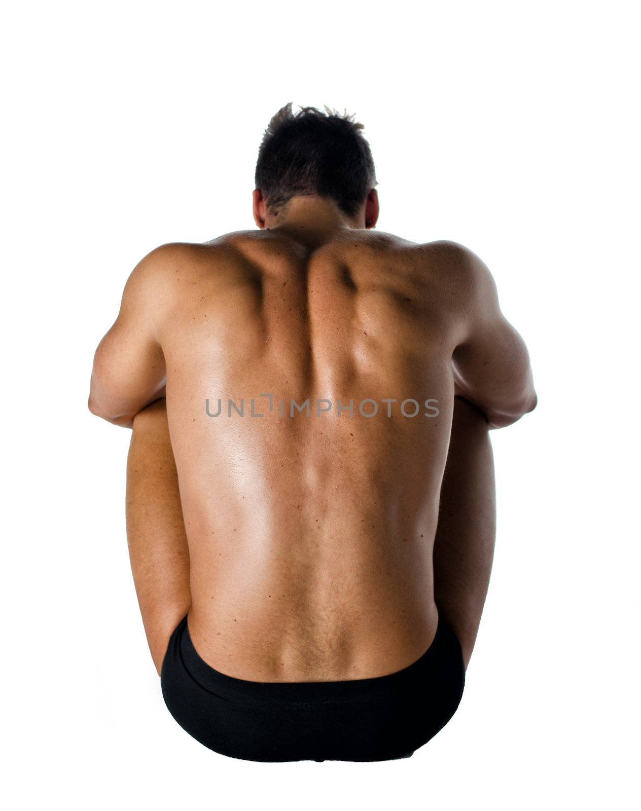 Muscular back of shirtless young man sitting on the floor, isolated on white background