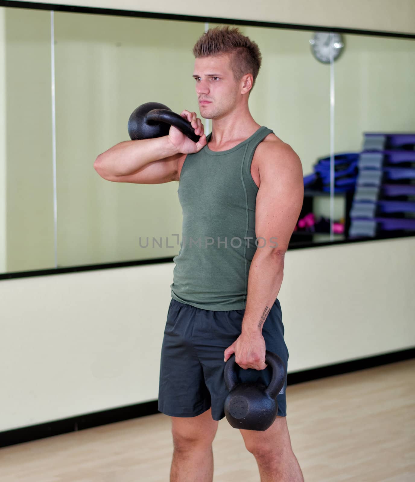 Young man working out with kettlebells in gym, standing