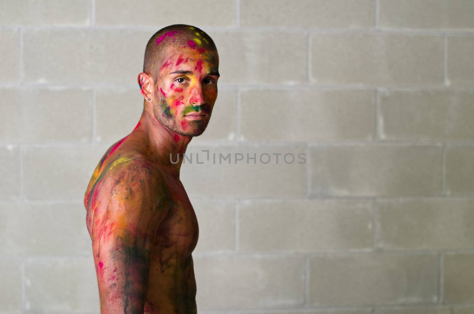 Handsome young man with skin painted all over with bright Holi colors