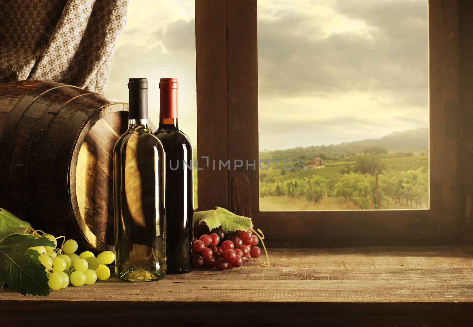 Wine bottles, barrels and vineyard in sunset