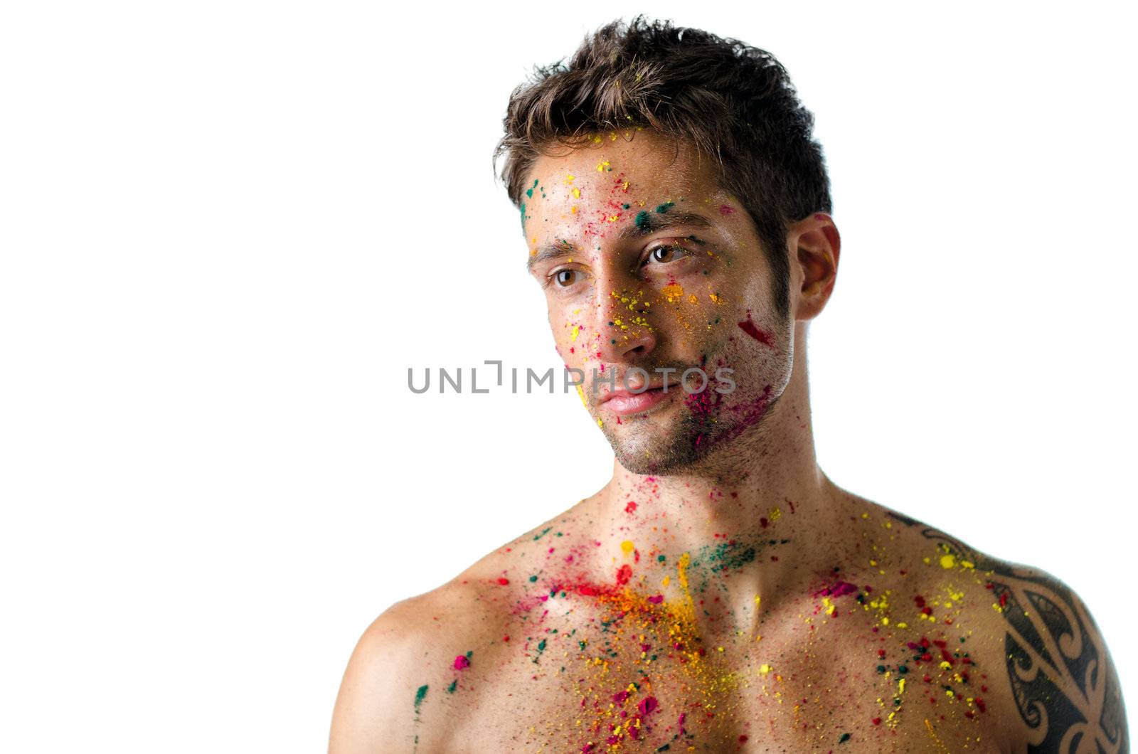 Attractive and athletic shirtless young man, skin painted all over with Holi colors, isolated on white