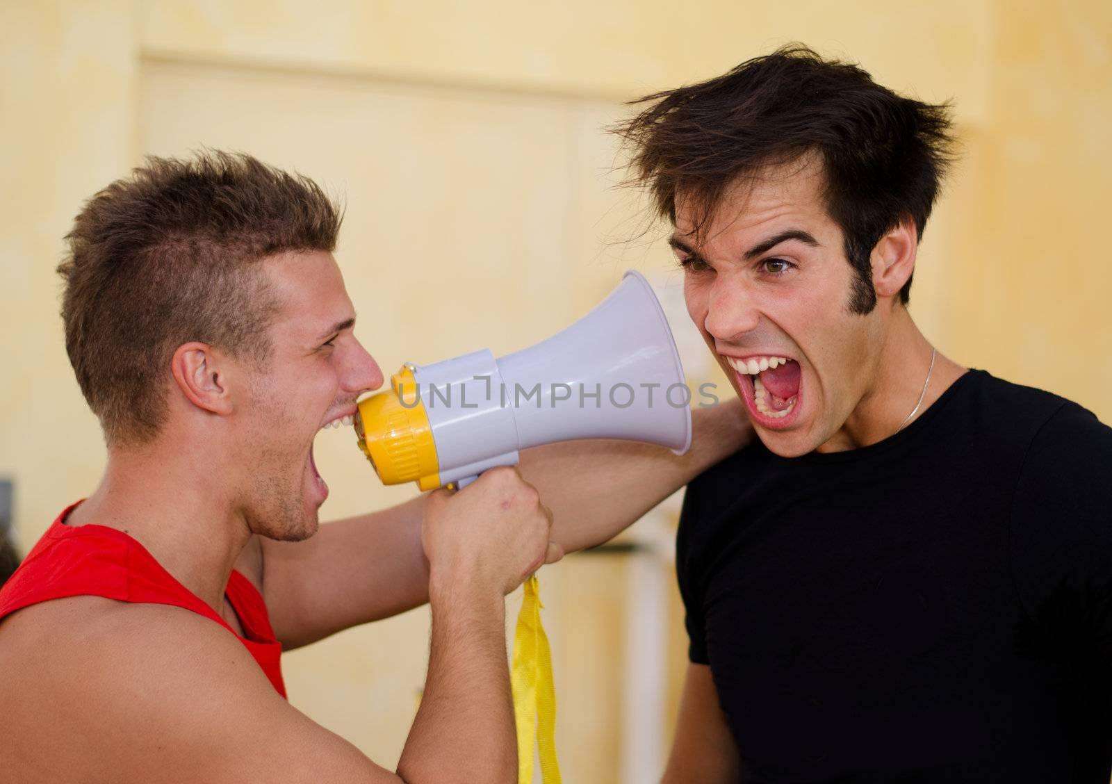 Personal trainer motivating male client by yelling against him with megaphone