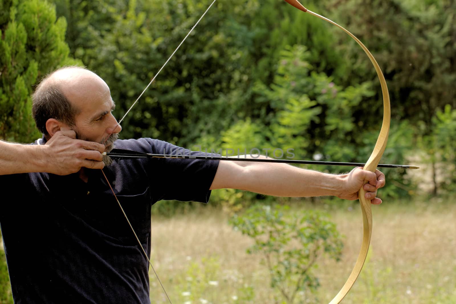 archery man shooting arrow with bow in the nature