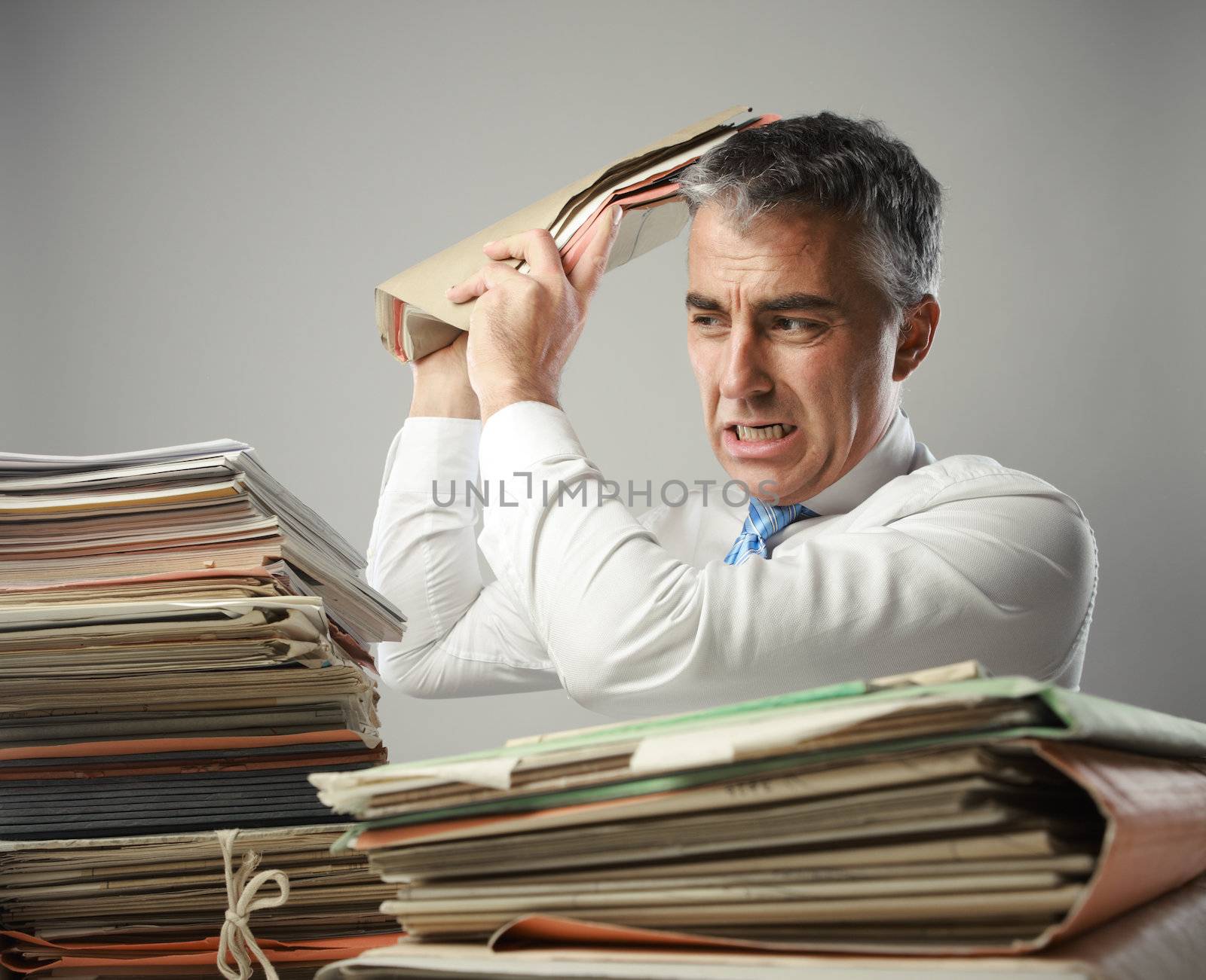 Stressed businessman, with a too much paperwork and files piled up on the table